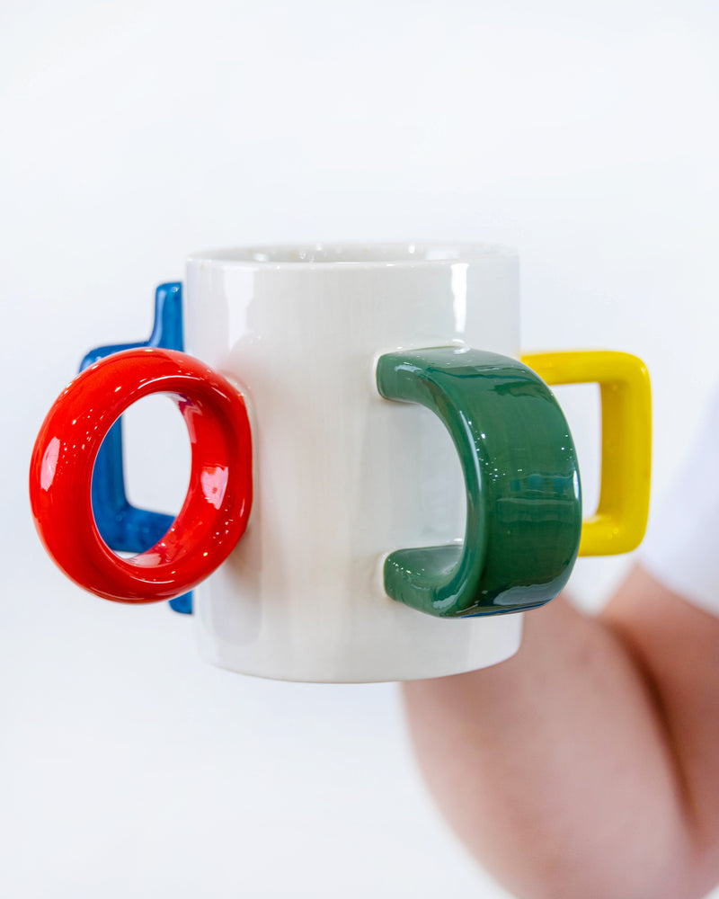 The Mood Mug held in one hand, showing red, green, yellow and blue handles