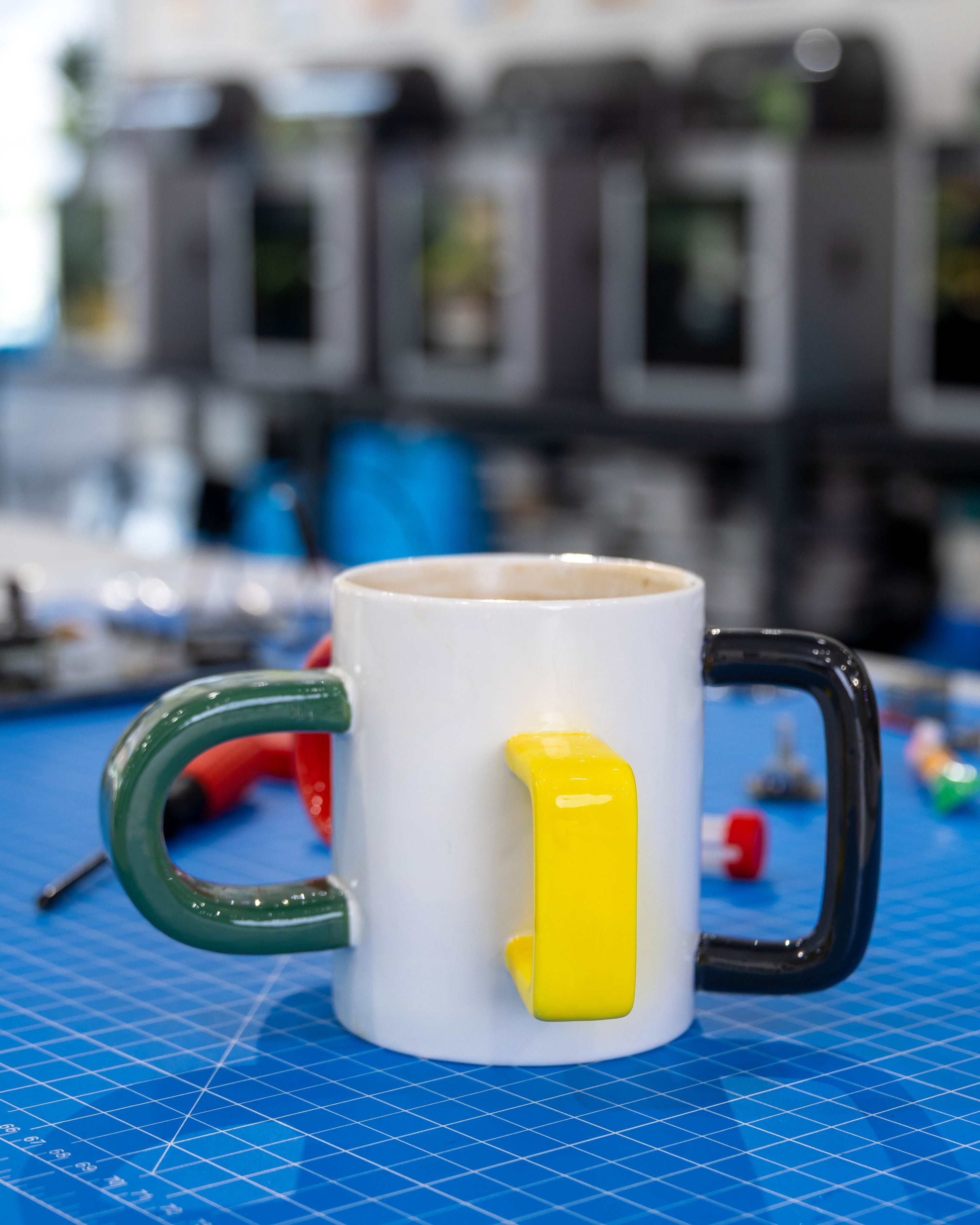 The Mood Mug on a blue cutting mat, showing green, yellow and black handles