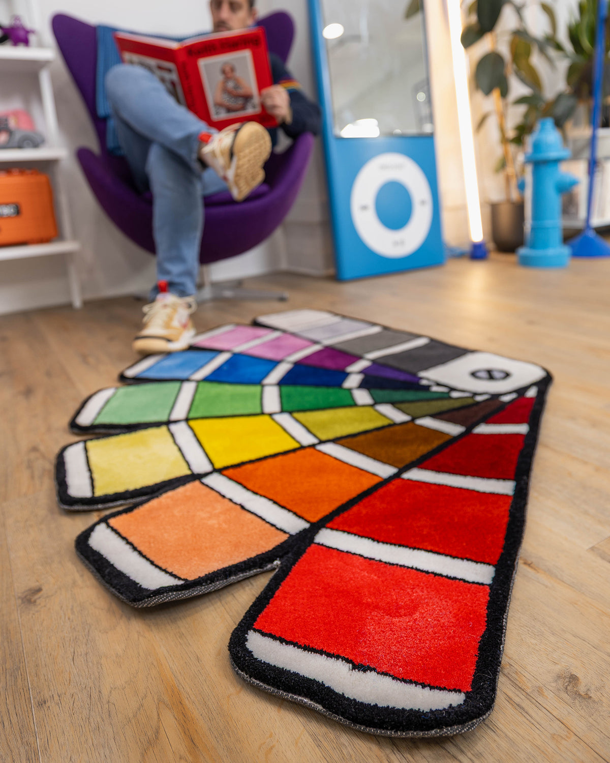 enotnaP Chart Rug on a wooden studio floor beside a purple chair.