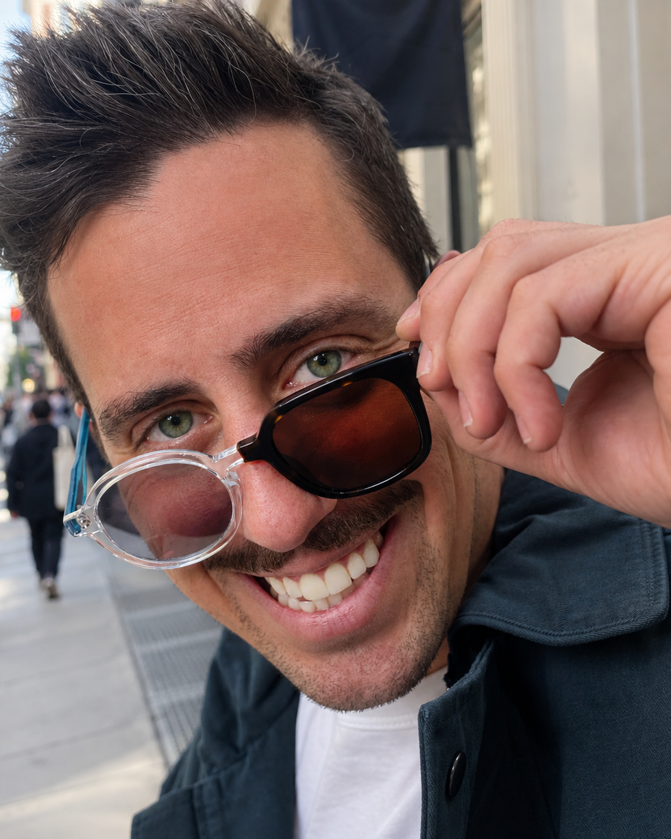 Matty wearing asymmetric Frankenstein Frames outdoors, with one round lens and one boxy lens.